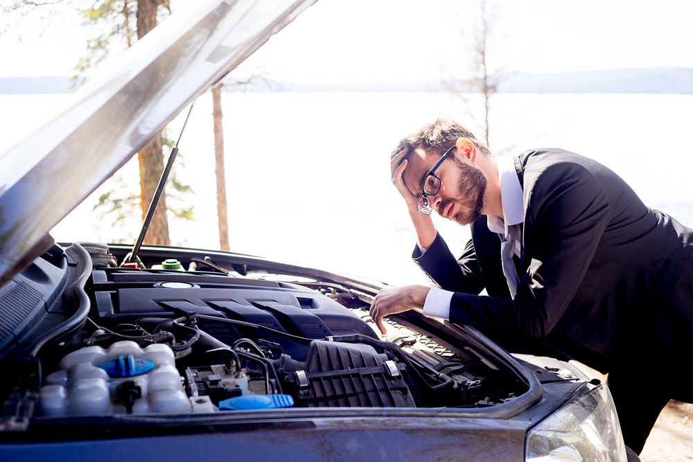 A person looking at the engine of a car needing engine repairs